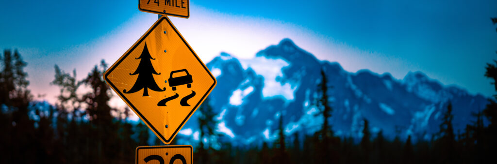 Winding road sign in Mount Baker National Park during sunset.